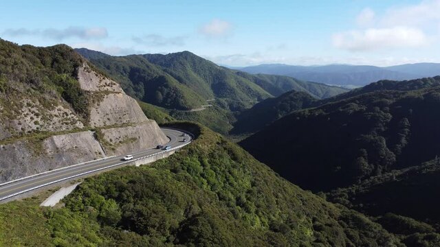 A static shot of a winding mountain road with cars driving on it. Rimutaka Hill Road, New Zealand.