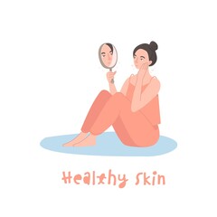 Young woman looking at herself in mirror sitting on a floor.