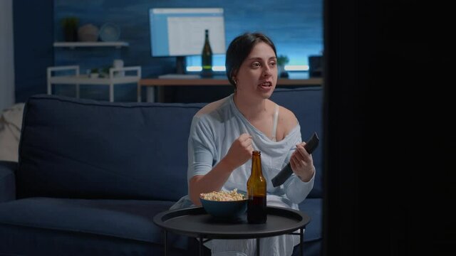 Excited proud woman football fan watching sport game supporting team talking alone, shouts of happiness after winning competition, eating popcorn, drinking beer, celebrating scoring of championship