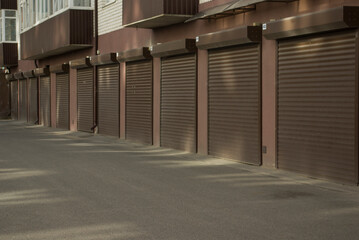Roller gates of brown garages on the first floor of a multi-storey building