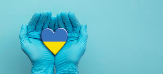 Doctors hands wearing surgical gloves holding Ukraine flag heart
