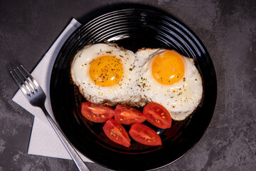 fried eggs and tomato slices, delicious breakfast, snack, yolk and protein food, background, top view, copy space, eat healthy raw materials. Scrambled eggs. Breakfast. Healthy eating. Close-up