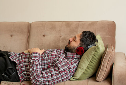 Profile View Of A Man Lying On A Couch And Falling Asleep While Listening To A Guided Meditation