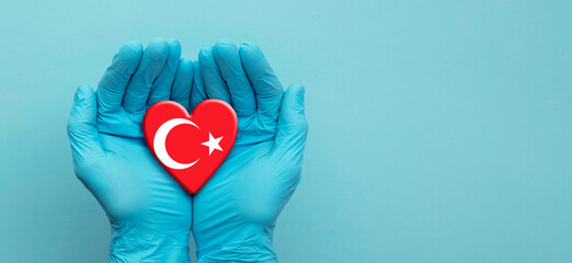 Doctors hands wearing surgical gloves holding Turkey flag heart