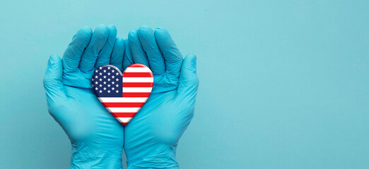 Doctors hands wearing surgical gloves holding USA flag heart