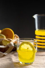 Refreshment  lemonade glass, orange fruit, wooden citrus squeezer , crystal jar on linen tablecloth. Summer beverage for hot day concept.