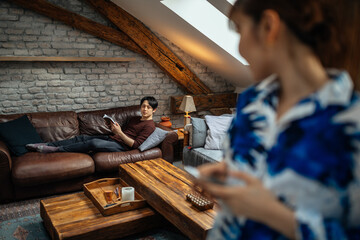 Fototapeta na wymiar Japanese woman using phone while her boyfriend chilling on bed