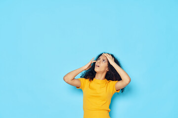 Obraz premium woman with curly hair in a yellow t-shirt holding her head emotions studio