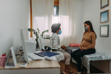Doctor with a pregnant woman in medical masks during an examinations