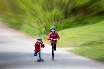 Obraz premium Children, brothers, riding scooters in the park together