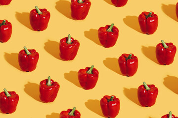 Pattern with fresh red bell peppers isolated on vibrant yellow background. Creative organic...
