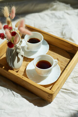 Fototapeta na wymiar Breakfast in bed, try with two cups coffee and flower in sunlight at home
