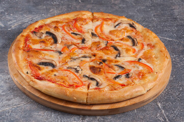 pizza with mushrooms and tomatoes on a wooden Board on a gray background
