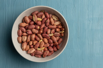 One bowl full of peeled peanuts on a blue background