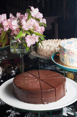 chocolate Sacher cake on a dark background with pink flowers