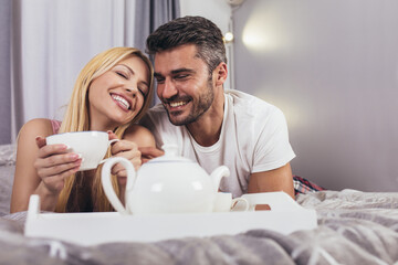 Cute couple having breakfast in bed in the bedroom