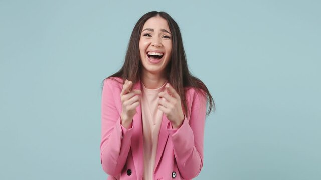 Excited cheerful fun young woman 20s years old wears pink jacket t-shirt look camera laugh smiling watch comedy movie pointing index finger on you isolated on pastel blue wall color background studio