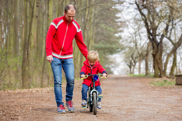 Little boy, learning how to ride a bike in the park - obrazy, fototapety, plakaty