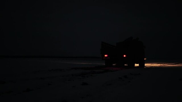 Night, low light, swamp, snow. Retro truck, old soviet military truck of world war ii transport. Soviet military vehicle for transporting soldiers. Driving along the roadway on paving stones. Winter