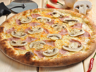 pizza with ham and mushrooms on a wooden table