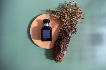Top view of dark male cologne bottle on the podium with wood piece and craft paper green...