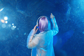 Beautiful woman with purple hair in futuristic costume. Blue neon light. Young girl in modern...