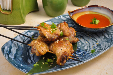 Asian chicken leg kebab on a bamboo stick with sauce