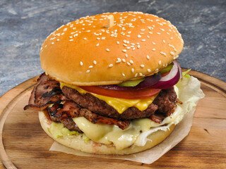Burger with two cutlets, bacon, vegetables and cheese