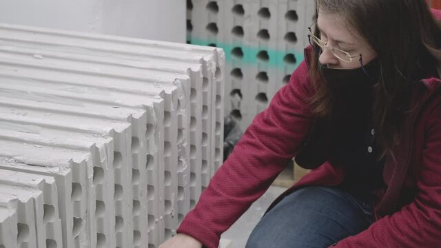 Woman wearing mask against virus buys foam concrete in building materials store. Concept of women independence, feminism, gender equality, repair and construction