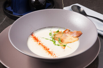 cream cheese soup decorated with paprika, jamon, micro greenery