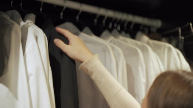 Woman chooses a shirt in the wardrobe closet at home