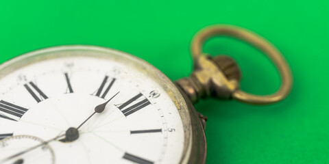 Close up view of old pocket watch on green background