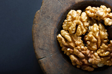 Fototapeta premium Walnuts in antique, wooden mortar.