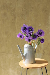 Bouquet of flowers in metal watering can, colored blue anemone.