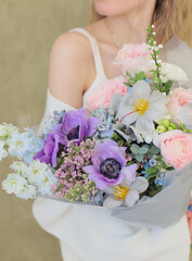 Young woman holding fresh bouquet of beautiful flowers in her hands. Beautiful flower bouquet wrapped in paper.