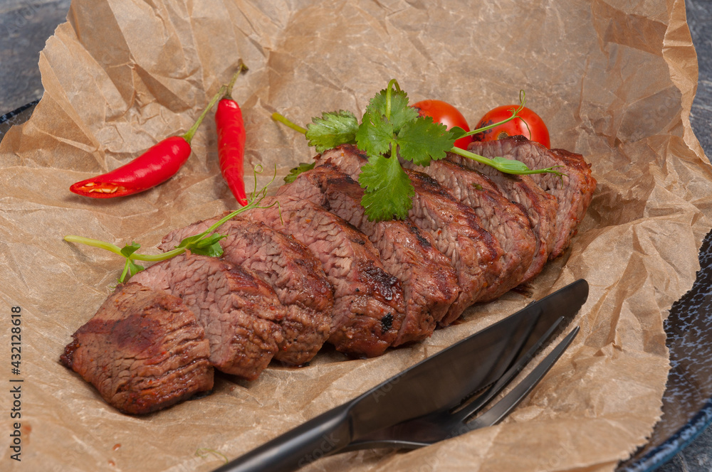 Wall mural beef steak on parchment decorated with pepper and herbs