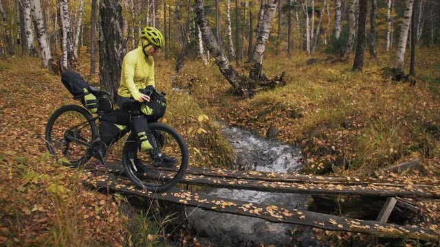 The woman travel on mixed terrain cycle touring with bikepacking. The traveler journey with bicycle bags. Sport tourism bikepacking.