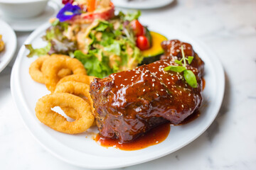 Grilled pork ribs with barbecue sauce and vegetables on a white plate