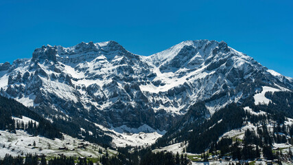 Fototapeta na wymiar Grosser Lohner und Mittagshorn bei Adelboden in den Schweizer Alpen, frisch verschneite Berge im Frühling, Schnee von gestern, beleuchtete und schwarze Felsen und glänzende Schneefelder im Kontrast