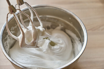 Whipped egg whites and other ingredients for cream on wooden table, closeup