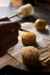 Chef hand making Mooncake a Chinese traditional pastry for Mid-Autumn festival. set on rustic wooden table.