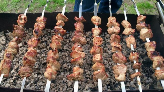 Close-up of grilling tasty dish on barbecue. Process of cooking yummy shashlik in nature. Delicious food on metal skewer in bbq. Time to picnic concept. Street food. Pork at the stake