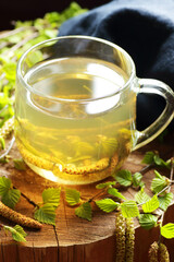 Herbal tea from birch earrings or blooming flowers with pollen on rustic wooden background, closeup, naturopathy, natural medicine and healthy healing drinks concept