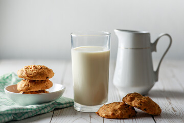 A fresh glass of milk with chocolate chip cookies on white wooden background. Healthy eating. Selective focus.