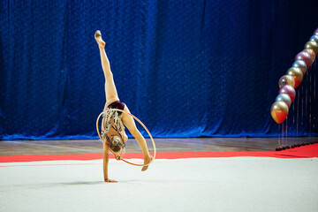 a gymnast girl performs with a hoop. flexible athlete performs a handstand at competitions