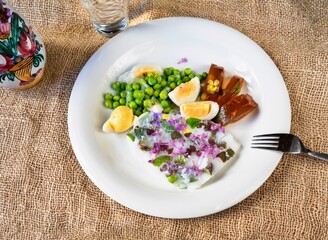 2 kinds of flower aspic, pea and egg on plate,fork and vase on jute.