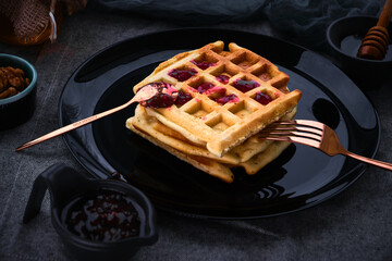 waffles with honey on a dark background
