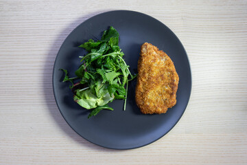 A plate of pork schnitzel and green salad.