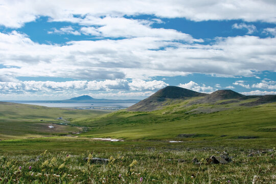 Summer Arctic landscape. View of the tundra and mountains. In the distance, the settlement of Ugolnye Kopi, Anadyr Airport and the Anadyr estuary. Chukotka, Siberia. Travel to the Far North of Russia.
