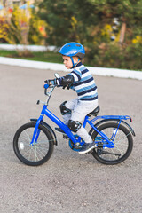 Fototapeta na wymiar A child in a helmet and protection in a bike ride on nature in the spring